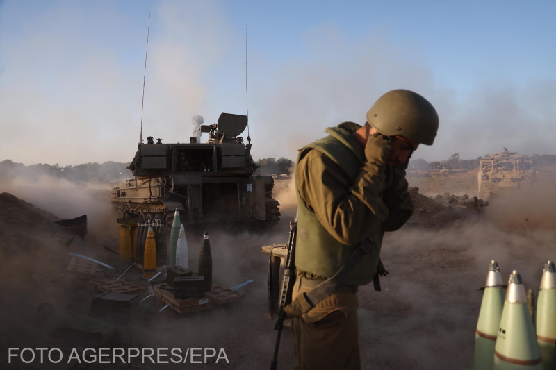 Egy izraeli katona befogja a fülét, miközben egy tüzérségi egység lövedékeket lő ki a gázai határ közelében, Izrael déli részén.