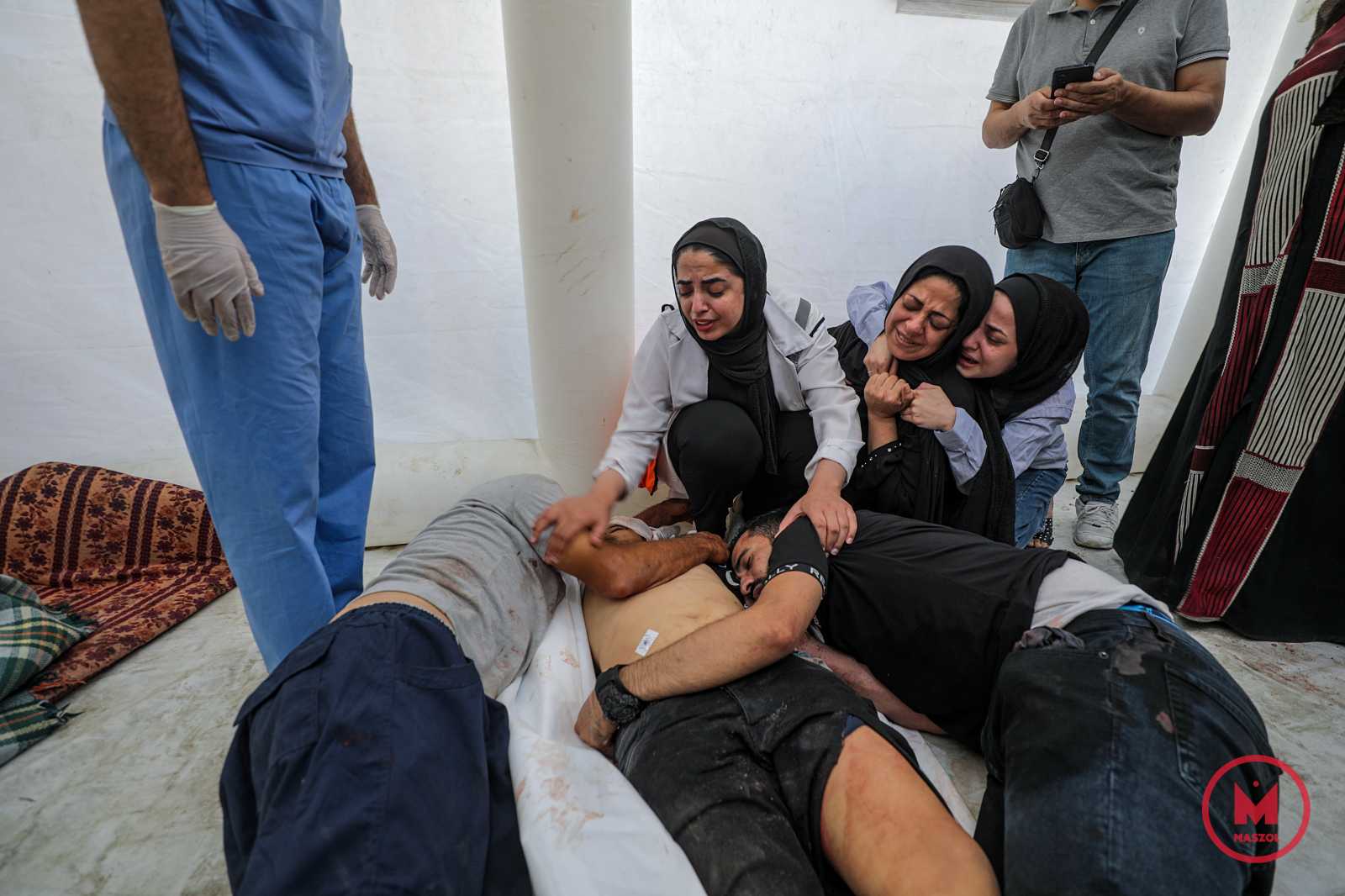 Halottjuk mellett gyászoló palesztinek. A gázai egészségügyi minisztérium szerint 500-an, egy másik gázai tisztviselő szerint 300-an halhattak meg, és rengeteg a sebesült. A kórház nemcsak sérültekkel volt tele, de több százan ide menekültek a bombázások elől is.