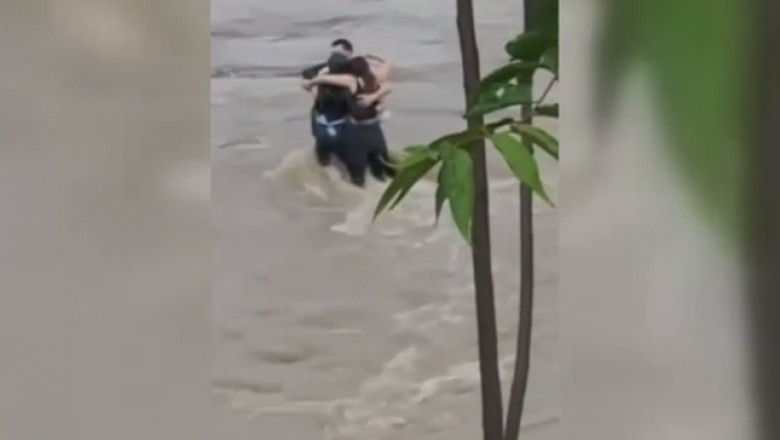 Képernyőmentés a videófelvételből, amely mutatja, ahogy a három fiatal összeölelkezve próbál ellenállni a sodrásnak