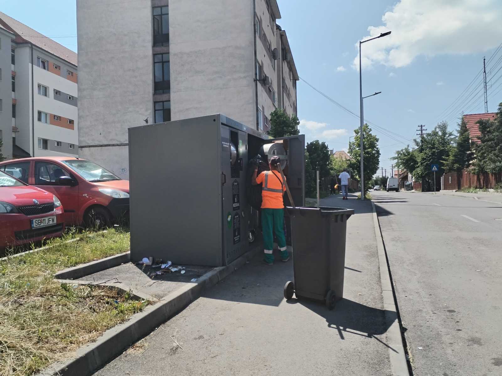 A hulladékgazdálkodási vállalat munkatársa a tárolóba pakolja a mellé helyezett szemetet