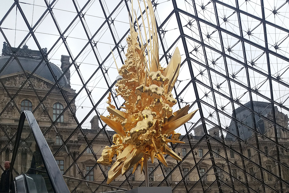 Trón a Louvre üvegpiramisa alatt, Kohei Nawa japán szobrászművész munkája. A 21 méter magas üvegpiramis 1989 óta a Louvre főbejárata, napjainkra nem csak a múzeum, hanem a város egyik szimbólumává vált. Szentségtörés volt a reneszánsz stílusú palota udvarán felépíteni, állítják a kritikusai, akik azért is utálják, mert nem egy francia, hanem I. M. Pei kínai-amerikai építész tervezte.
