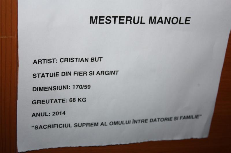 A Manole-szobor talapzatán olvasható szöveg. A mottó magyarul: 