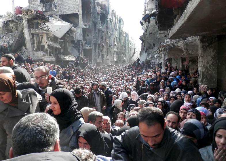 Palesztin menekültek élelmiszersegélyért állnak sorban Damaszkusz külvárosában. 2014. január 31.