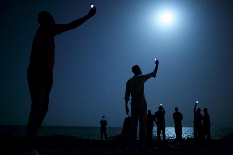A World Press Photo nyertes képén afrikai menekültek próbálnak térerőhöz jutni mobiltelefonjaikkal a dzsibuti tengerparton, hogy otthon maradt szeretteikkel beszélni tudjanak. A kelet-afrikai országba rengeteg menekült érkezik, akik onnan Európába akarnak