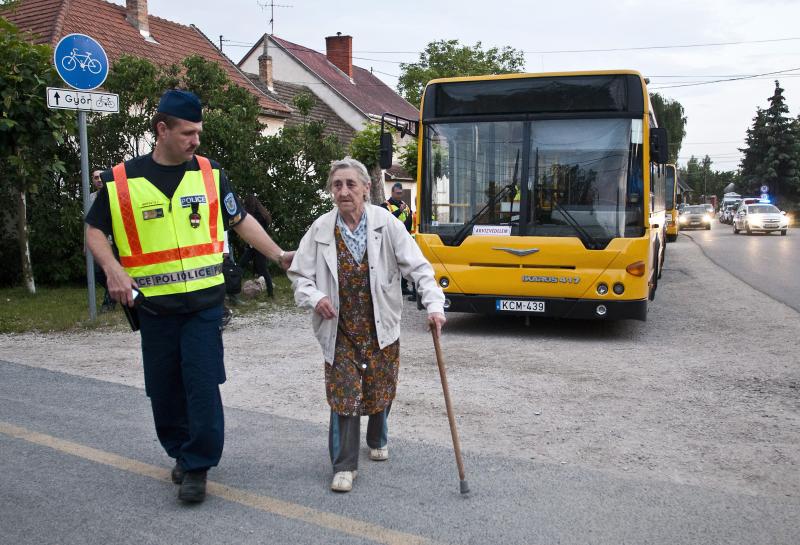 Özv. Takács Ferencnét rendőr kíséri a buszhoz, miután óvintézkedésként elrendelték Győrújfalu kitelepítését