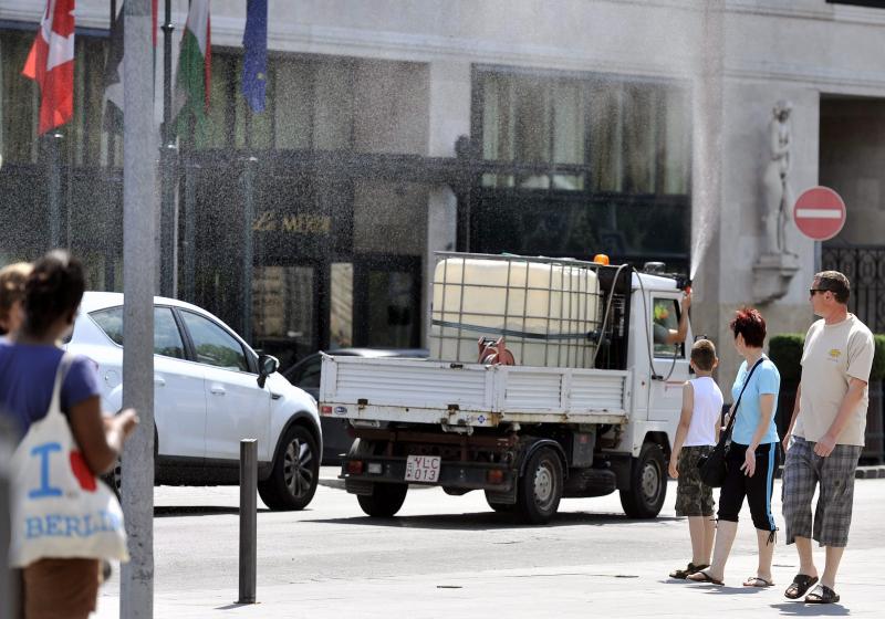 Egy locsolójármű sofőrje vízpermettel locsolja a járókelőket a belvárosi Erzsébet téren, a Le Méridien Budapest szálló előtt 2013. június 17-én.